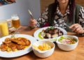 Mesa con platos de carne en salsa, puré, ensalada fresca y bebidas en el interior de madera del Restaurante 3 Soles.