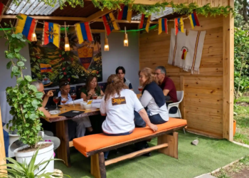 Grupo de docentes disfrutando de un almuerzo en un kiosco privado de madera decorado con banderas de Colombia en el Restaurante 3 Soles.