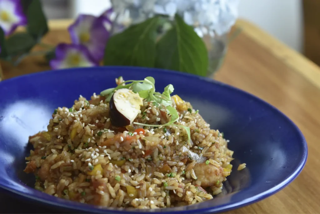 Arroz chaufa peruano con semillas de sésamo y brotes, servido en un plato azul en el Restaurante 3 Soles, Chía.