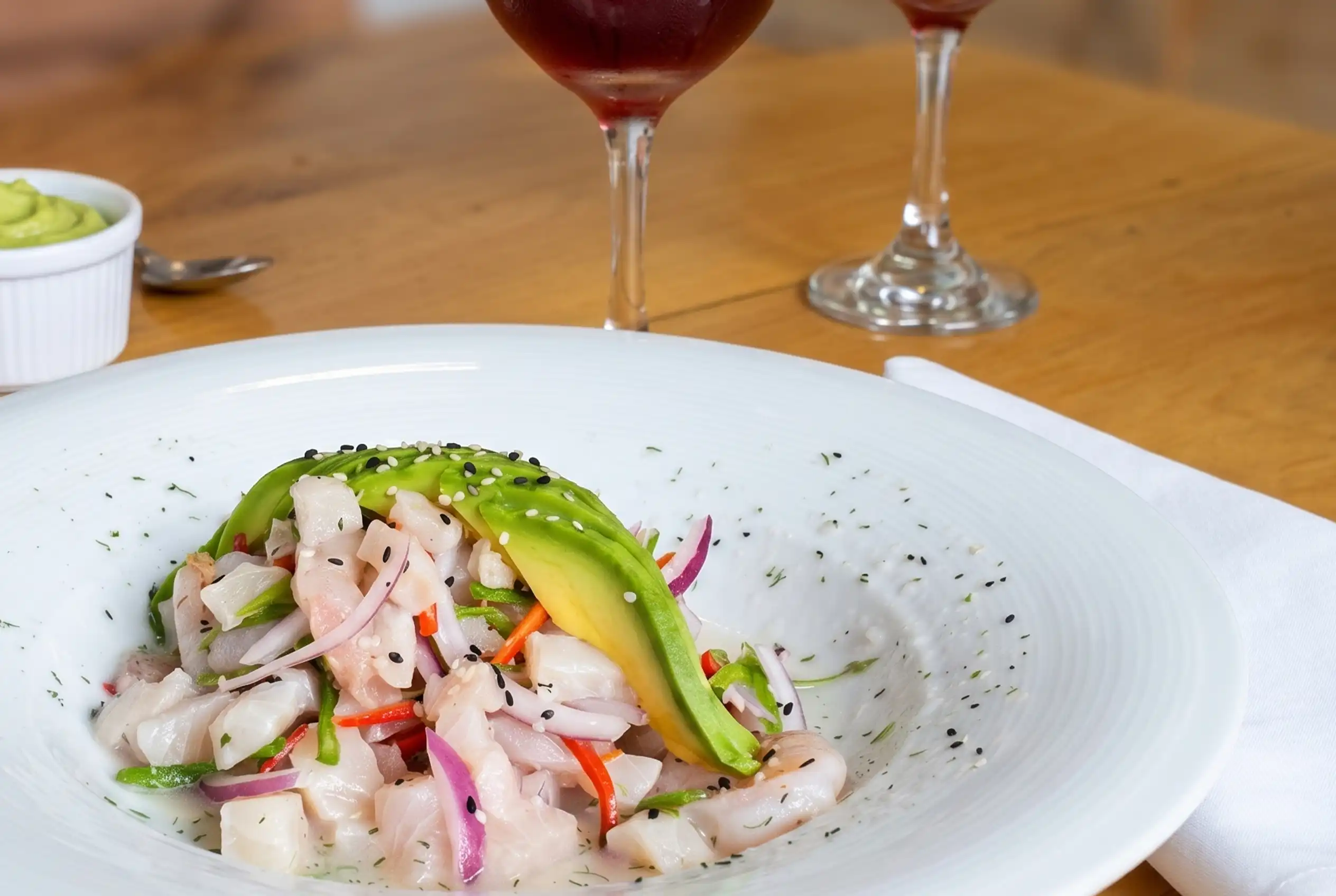 Ceviche peruano fresco con láminas de aguacate y semillas de sésamo, servido en el Restaurante 3 Soles.