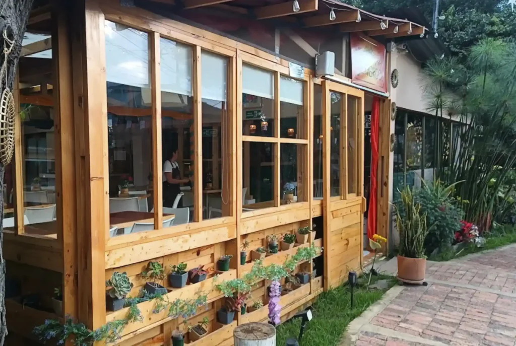Fachada rústica de madera del Restaurante 3 Soles en Chía, con ventanales grandes y un jardín vertical de suculentas.