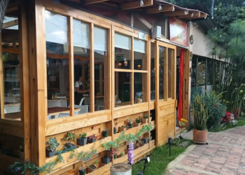 Fachada rústica de madera del Restaurante 3 Soles en Chía, con ventanales grandes y un jardín vertical de suculentas.