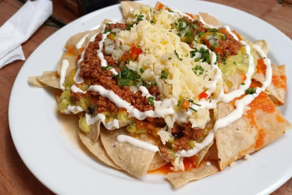 Plato generoso de nachos crujientes cubiertos con carne molida, queso rallado, crema agria y guacamole en Restaurante 3 Soles.
