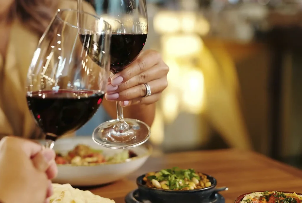Primer plano de una pareja brindando con copas de vino tinto durante una cena romántica en el Restaurante 3 Soles, Chía.