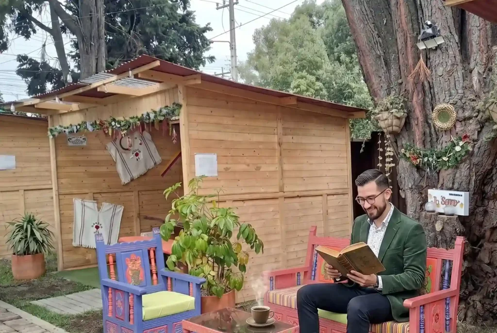 Un hombre con chaqueta verde lee un libro en una colorida banca de madera en la terraza del Restaurante 3 Soles.