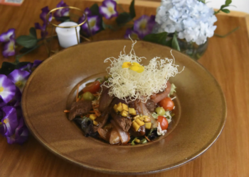 Elegante plato de cocina fusión peruana con lomo, vegetales frescos y nido de arroz crocante, decorado con flores en el Restaurante 3 Soles.