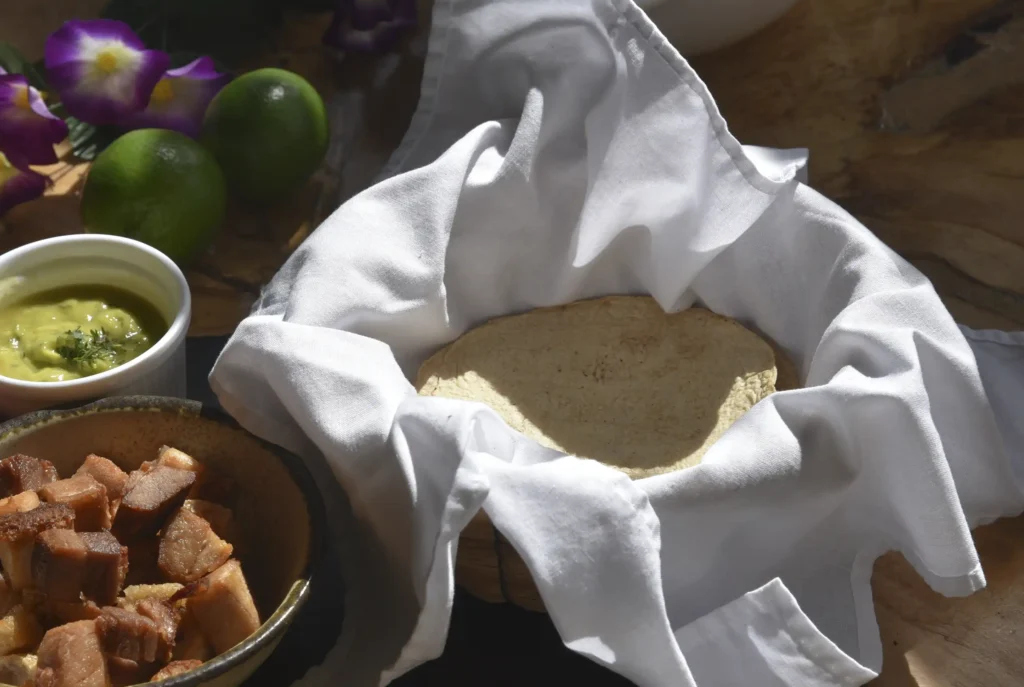 Tortillas de maíz recién hechas servidas en paño blanco con chicharrón crocante y guacamole, la esencia de la comida mexicana en Restaurante 3 Soles.
