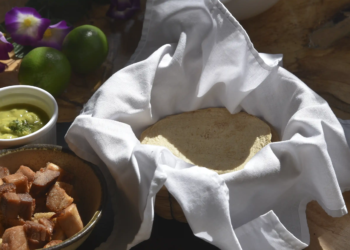 Tortillas de maíz recién hechas servidas en paño blanco con chicharrón crocante y guacamole, la esencia de la comida mexicana en Restaurante 3 Soles.