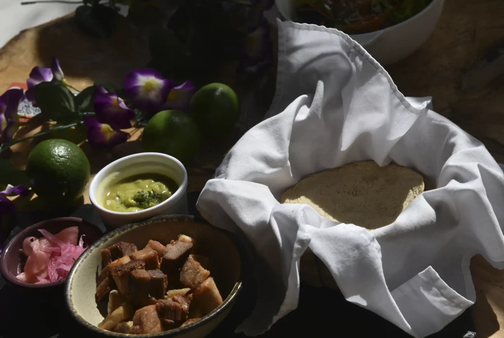 Tortillas de maíz artesanales calientes servidas con chicharrón crocante, guacamole y cebollas encurtidas en Restaurante 3 Soles.