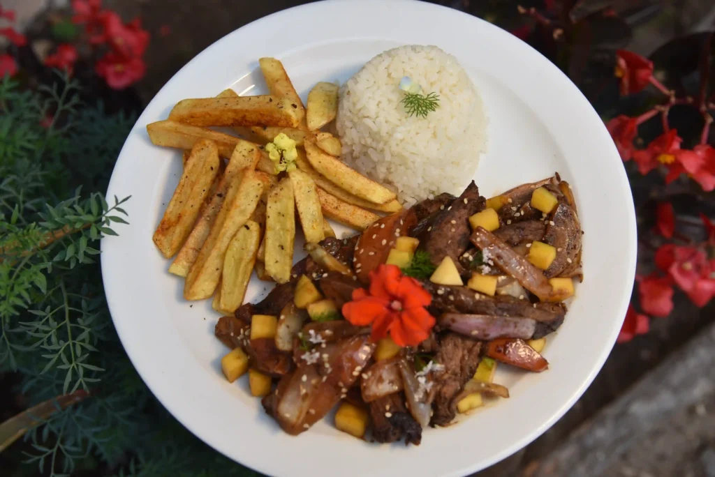 Lomo saltado con mango, papas sazonadas y arroz, fusión peruano-latina en Restaurante 3 Soles