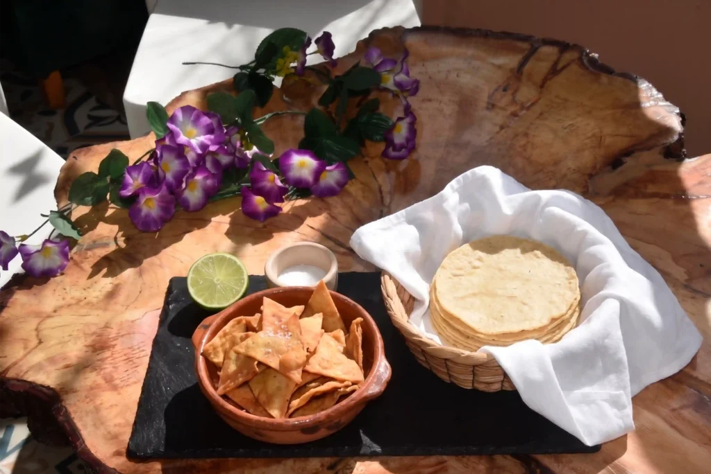 Bowl de barro con totopos y canasta de tortillas de maíz sobre mesa campestre en 3 Soles.