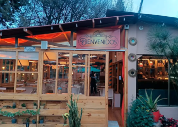Entrada de 3 Soles con letrero de bienvenidos y salón iluminado al atardecer
