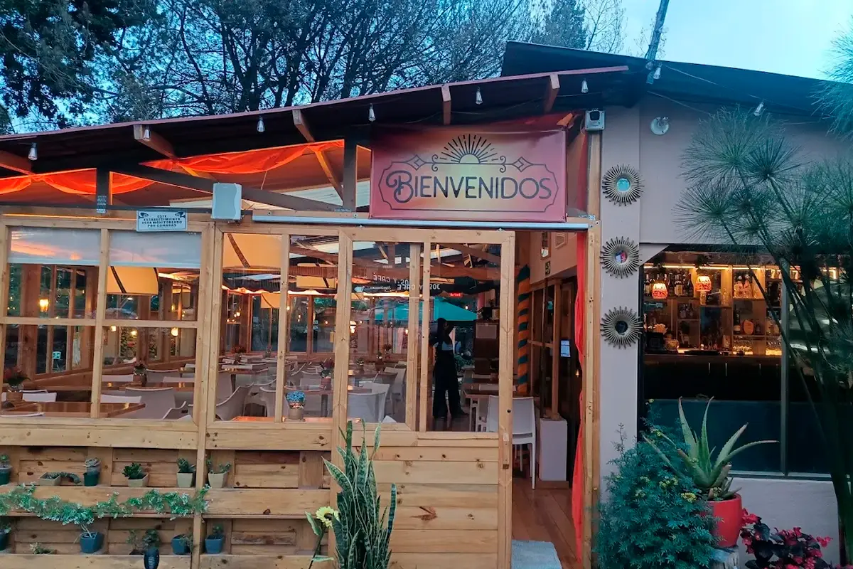 Entrada de 3 Soles con letrero de bienvenidos y salón iluminado al atardecer