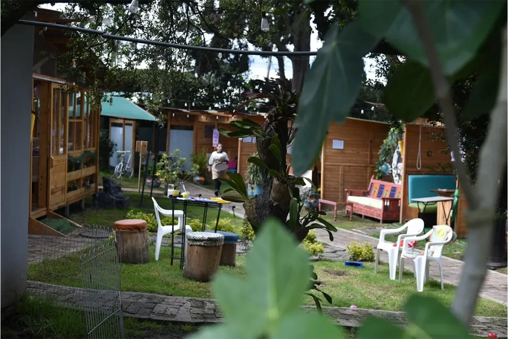 Vista del jardín exterior de 3 Soles con cabañas y mesas entre árboles en Chía