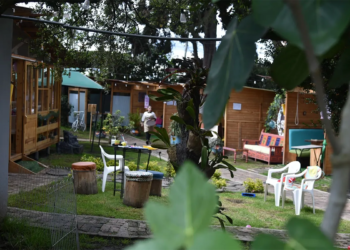 Vista del jardín exterior de 3 Soles con cabañas y mesas entre árboles en Chía