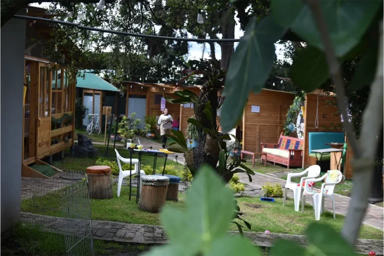 Vista del jardín exterior de 3 Soles con cabañas y mesas entre árboles en Chía