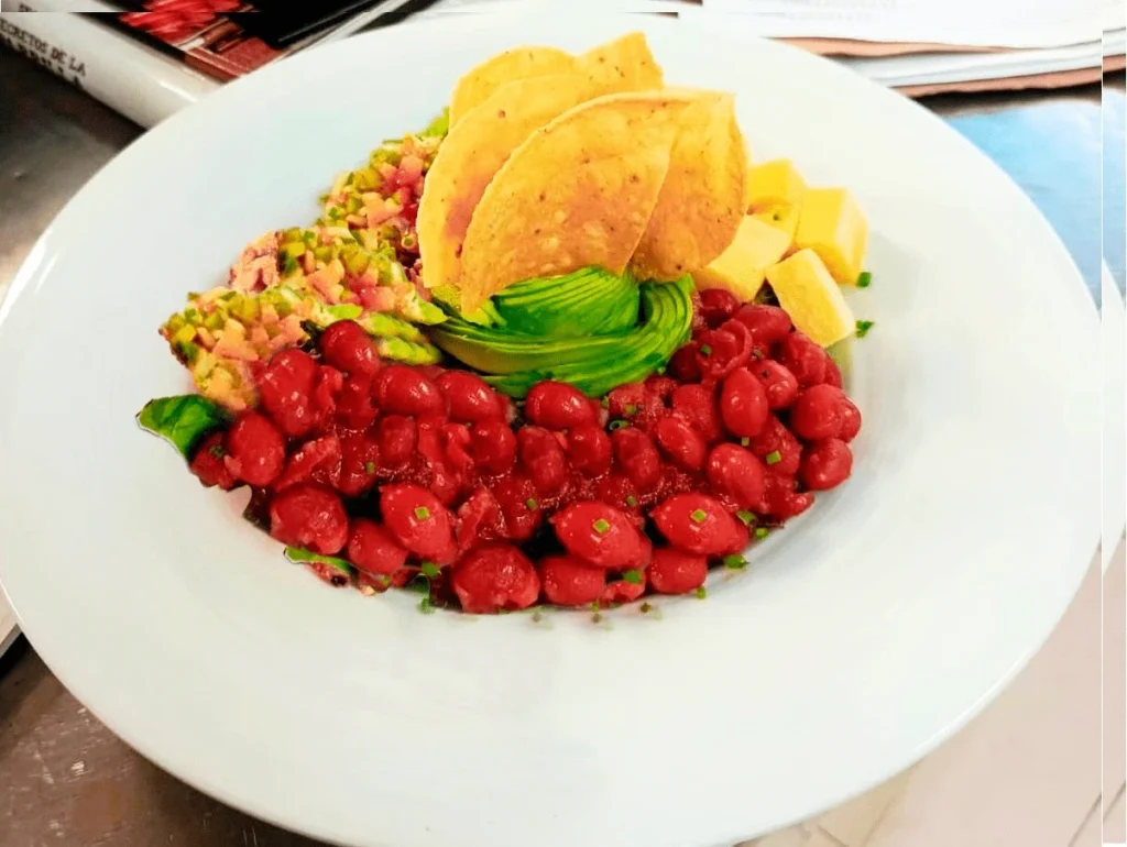 Plato de ensalada mexicana vegetariana con frijoles, aguacate, totopos y queso en restaurante 3 Soles.