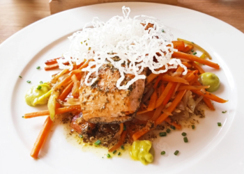 Filete de salmón a la mantequilla, limón y perejil servido sobre verduras en un restaurante de Chía.