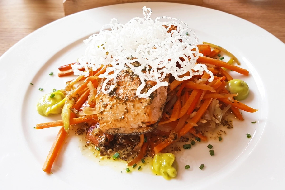 Filete de salmón a la mantequilla, limón y perejil servido sobre verduras en un restaurante de Chía.