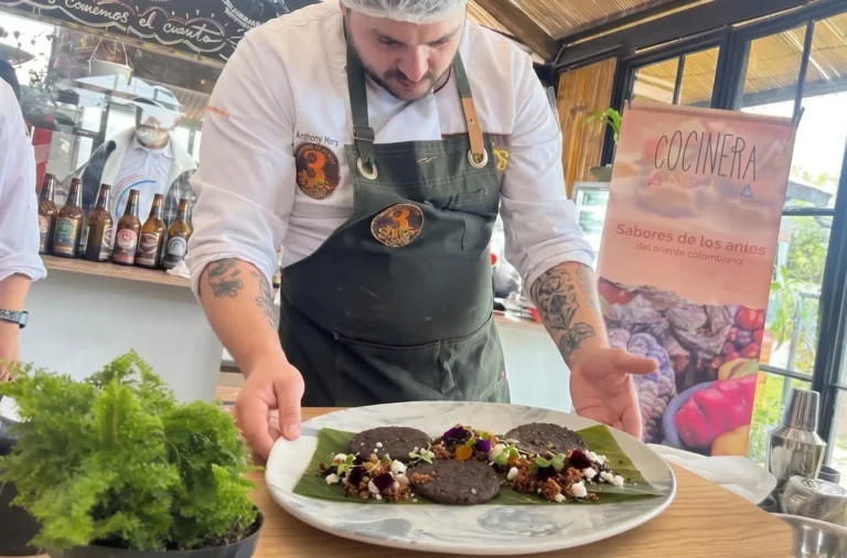 Chef Anthony Mora presentando su plato en el Reto Gastronómico 2026, servido sobre una hoja de plátano con sabores del oriente colombiano.
