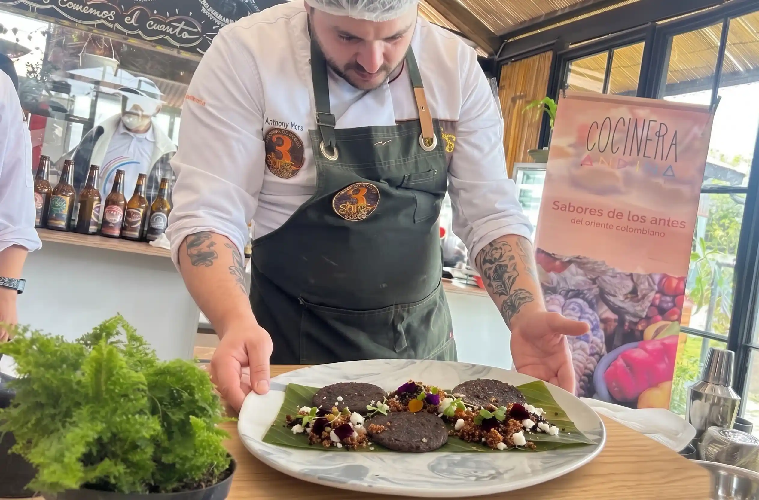 Chef Anthony Mora presentando su plato en el Reto Gastronómico 2026, servido sobre una hoja de plátano con sabores del oriente colombiano.