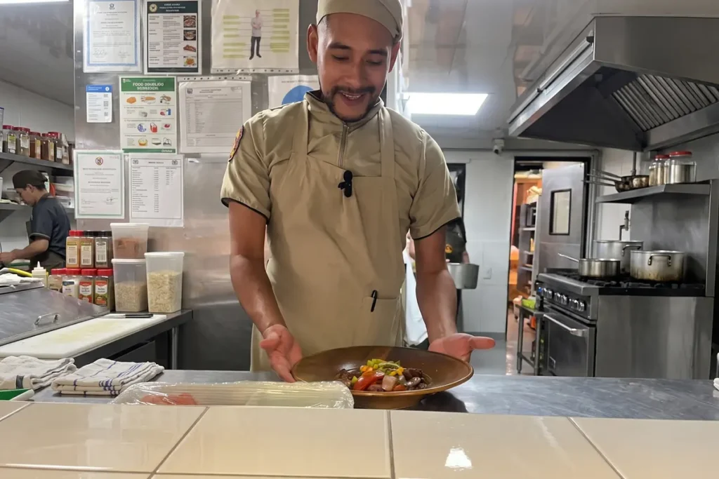 Chef presentando un plato recién preparado en la cocina de un restaurante en Chía durante una velada especial.