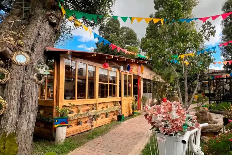 Wooden rustic restaurant exterior in Chía decorated with colorful bunting flags and outdoor plants.