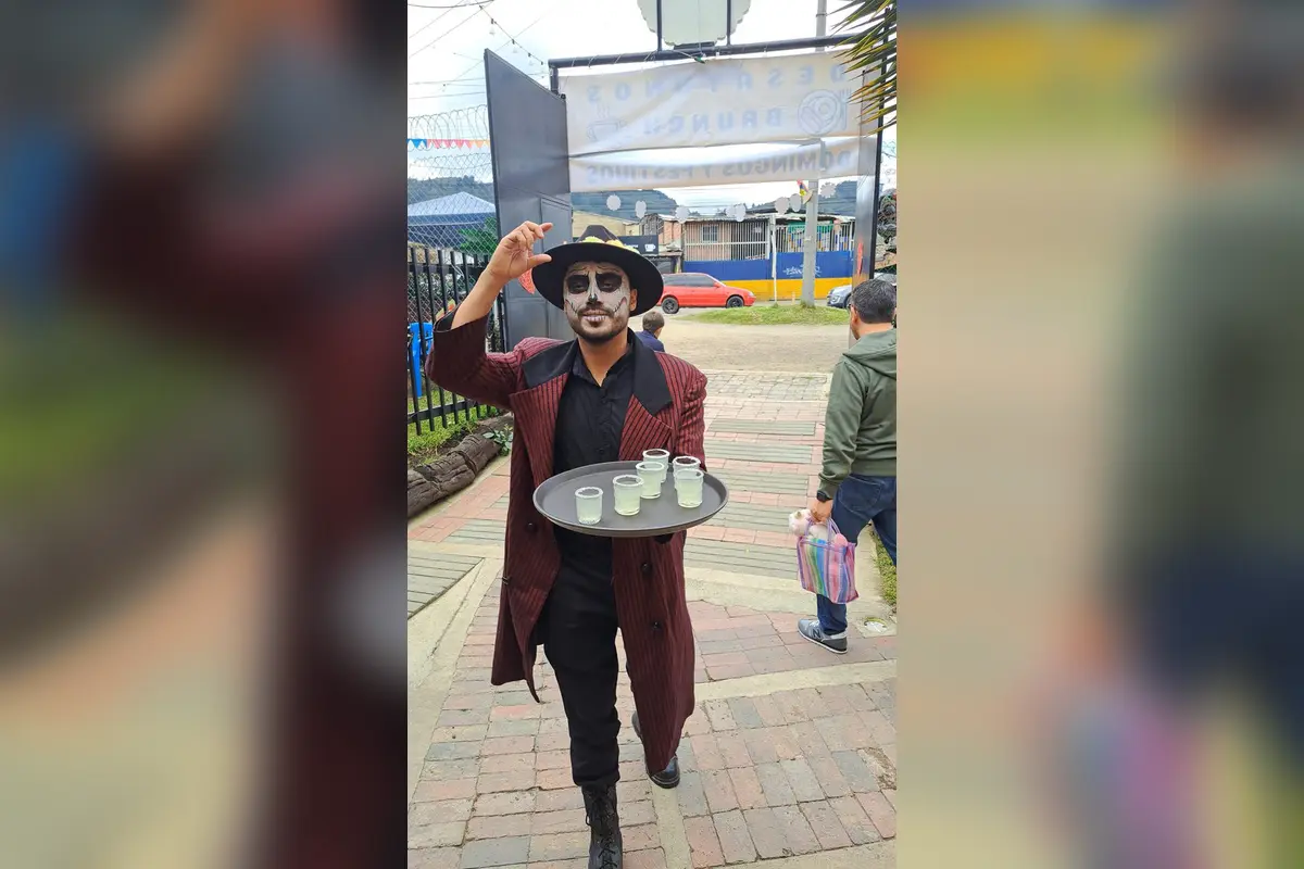 Waiter dressed as catrin serving drinks during day of the dead event at a restaurant in chia.