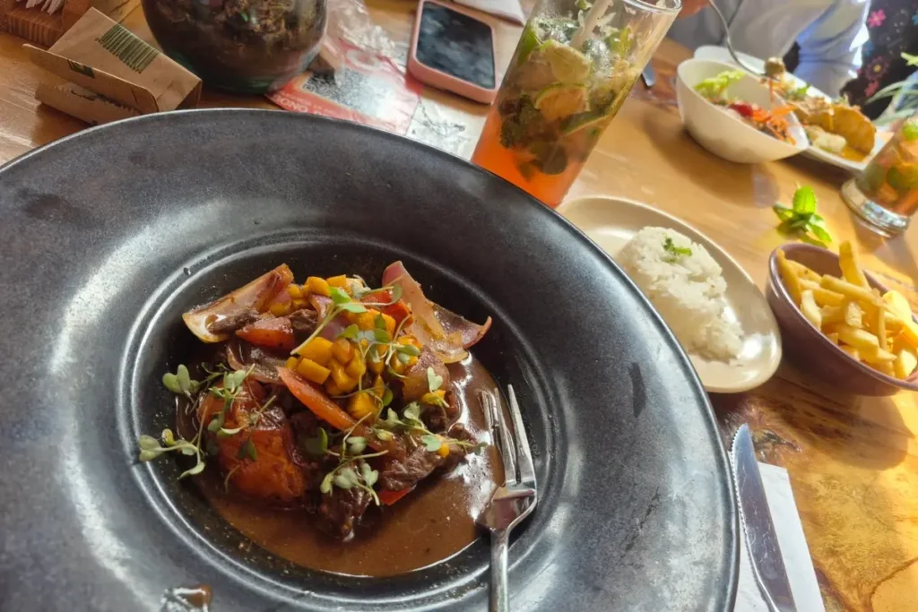 Plato de lomo saltado gourmet acompañado de arroz, papas fritas y cóctel en un restaurante de Chía.