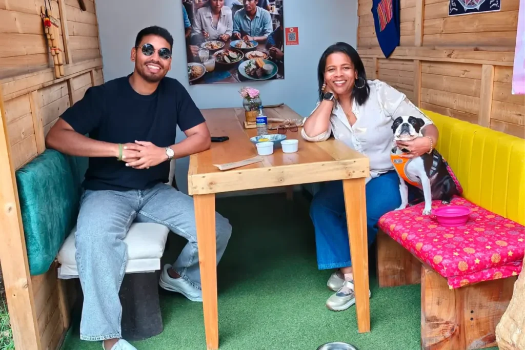 A man and a woman smiling at a wooden table with their dog inside a pet friendly restaurant in chia.