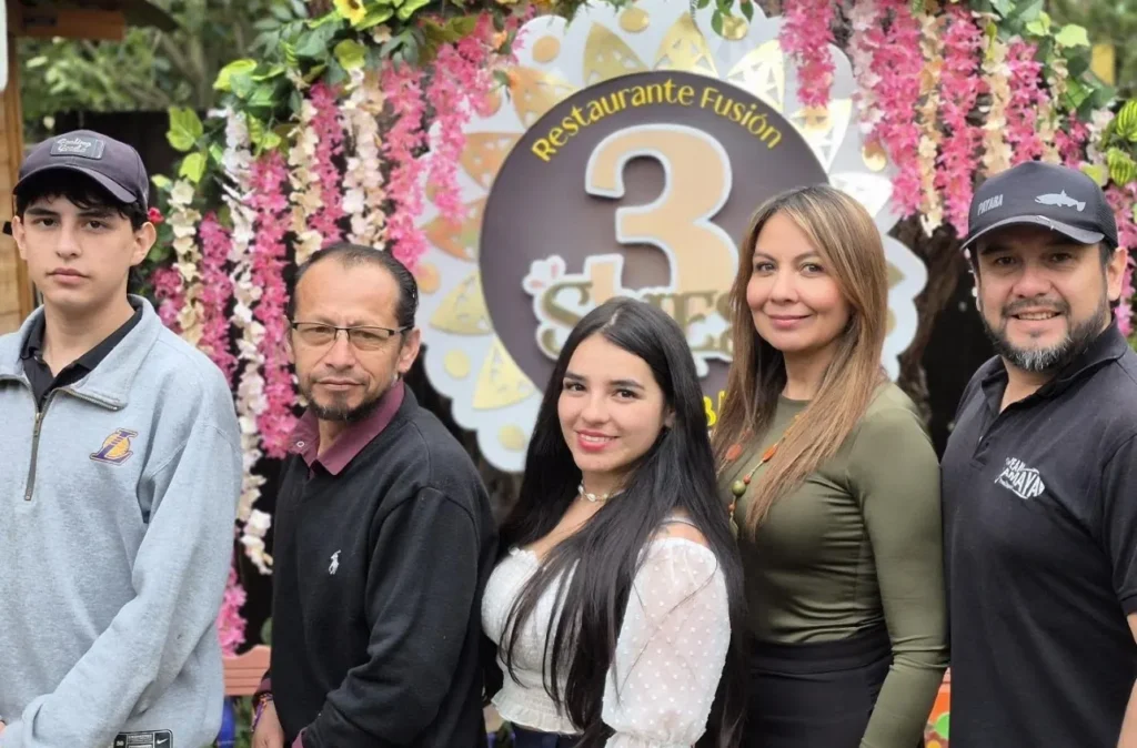 Familia posando frente al letrero decorado con flores del restaurante 3 Soles en Chía.
