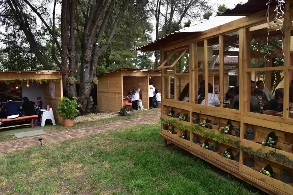 Cabañas de madera y zonas al aire libre rodeadas de áreas verdes en restaurante campestre de Chía.